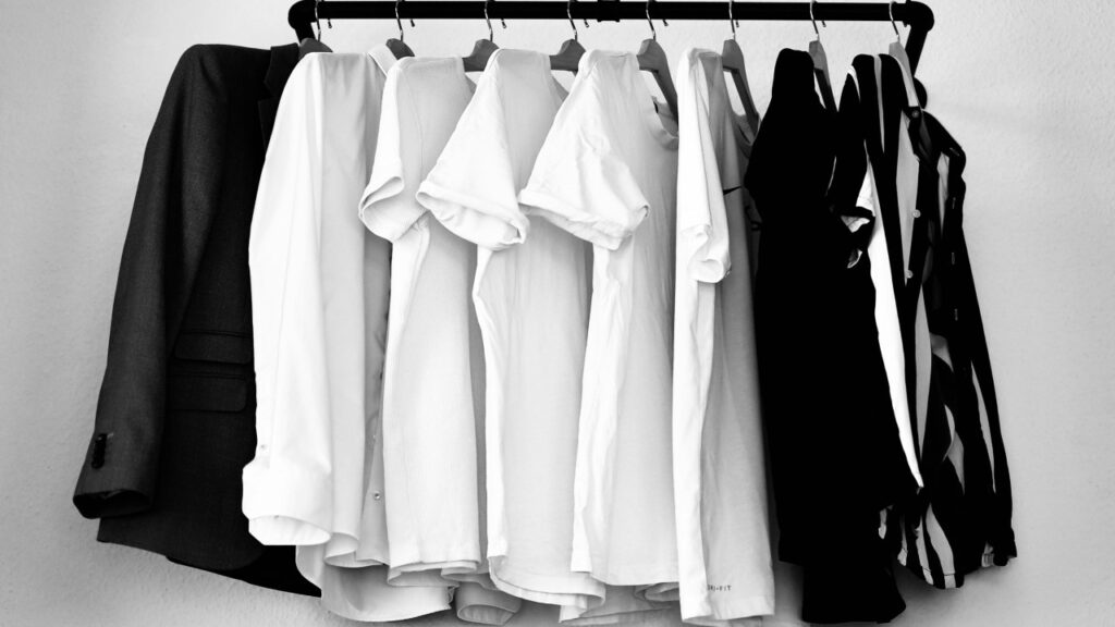 Prendas en tonos neutros colgadas en un perchero, fondo y estética de armario minimalista.