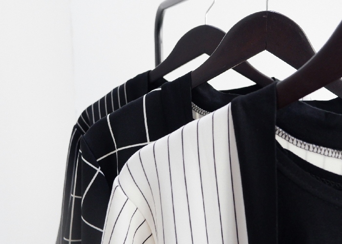 Camisas de rayas y prendas colgadas en perchas, imagen de armario ordenado y moda casual.