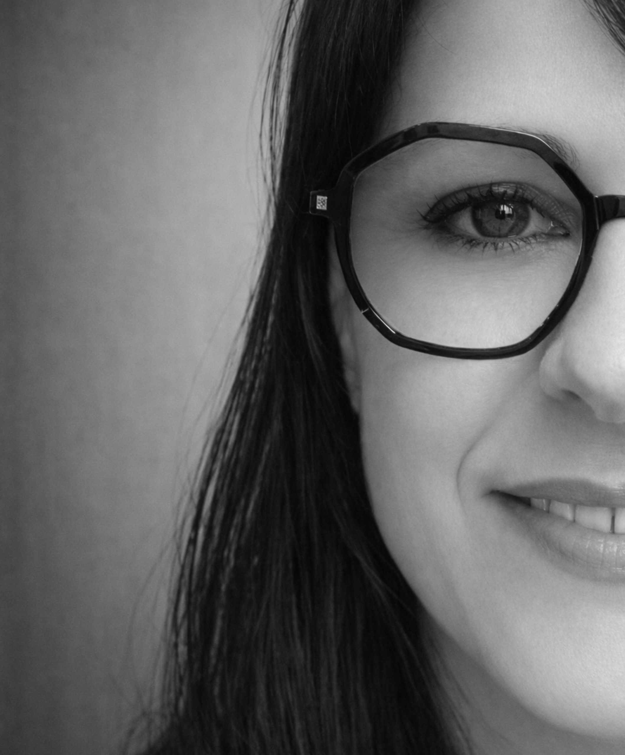 Primer plano en blanco y negro de mujer con gafas, imagen cercana y profesional.