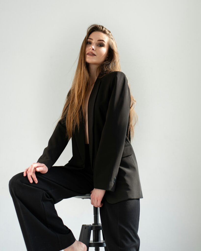 Mujer sentada con blazer negra y pantalón negro, look elegante y minimalista.